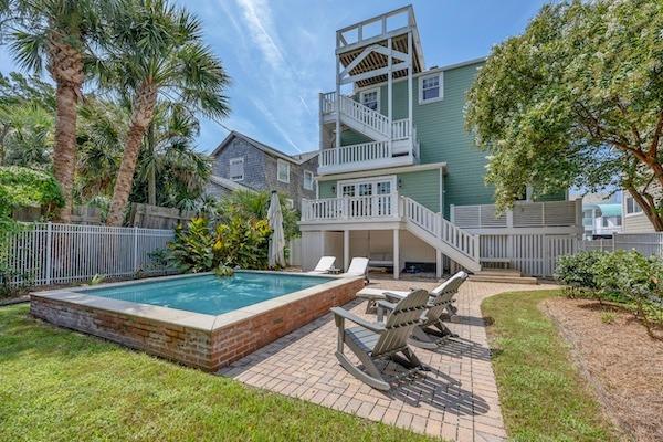Private backyard soaking pool with lounge chairs and palm trees at C Street Classic in Wrightsville Beach.